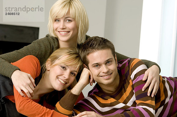 Porträt eines jungen Mannes  der mit zwei jungen Frauen lächelt