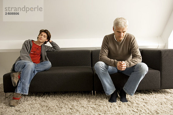 Der reife Mann und sein Sohn sitzen auf einer Couch.