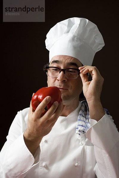 Stereotypischer Koch starrt auf eine rote Paprika