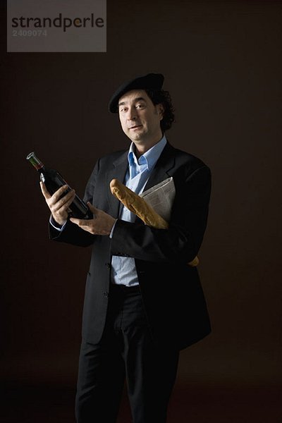 Ein stereotyper Franzose mit einer Flasche Wein  Baguette und einer Zeitung.