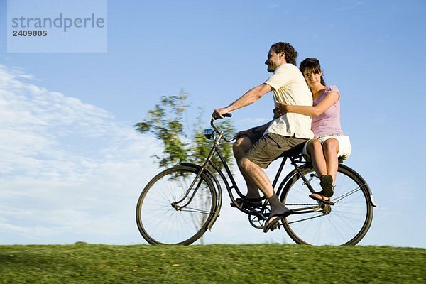 Ein Mann auf dem Fahrrad und eine junge Frau auf dem Rücken.