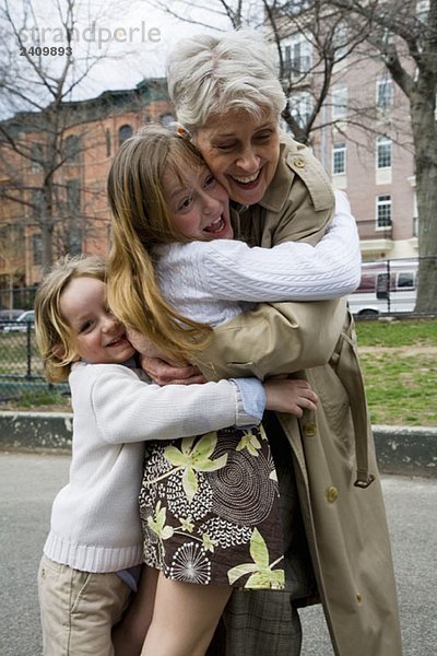 Enkelkinder umarmen ihre Großmutter