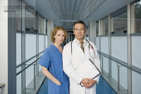 Zwei Mitarbeiter des Gesundheitswesens posieren in einem Krankenhauskorridor