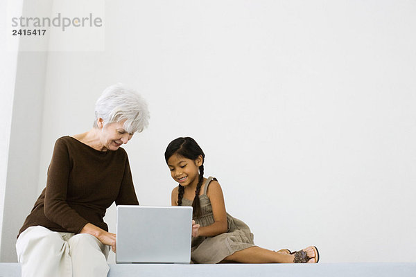 Seniorin mit Laptop und kleinem Mädchen