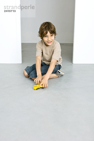 Junge spielt mit Spielzeugwagen