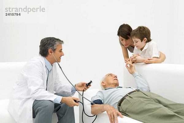 Arzt  der den Blutdruck eines älteren Mannes misst  Familienbeobachtung