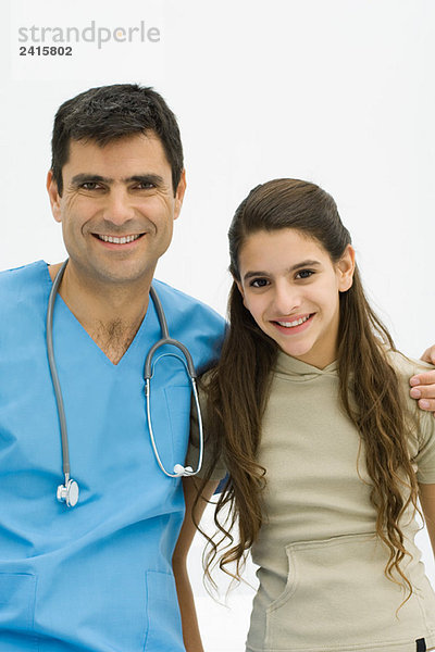 Arzt mit Arm um die Schulter des Mädchens  beide lächelnd vor der Kamera