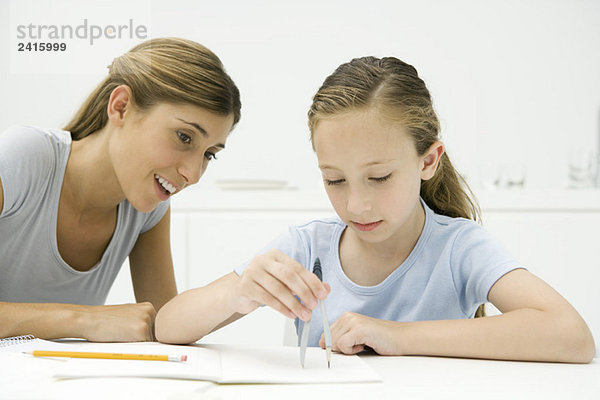 Mädchen bei den Hausaufgaben  mit dem Zeichenkompass  Mutter beim Zuschauen