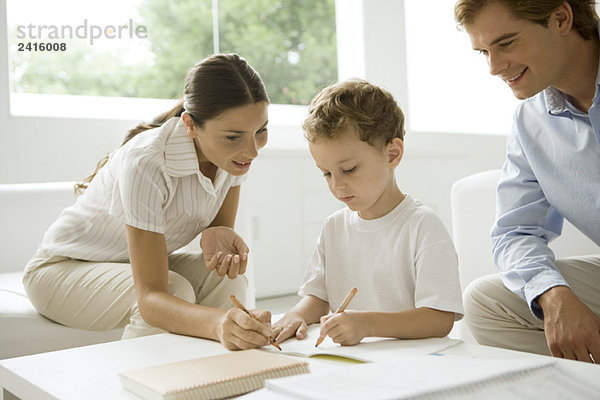 Eltern helfen dem kleinen Jungen bei seinen Hausaufgaben