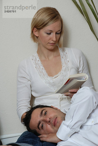 Junges Paar  Frau beim Lesen  Männerkopf auf dem Schoß liegend
