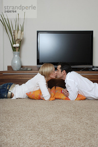Junges Paar küsst sich vor dem Fernseher