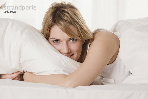 Blonde Frau entspannt im Bett  lächelnd  Portrait