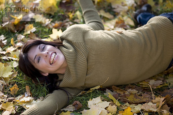 Brünette Frau entspannt auf Herbstlaub  Portrait