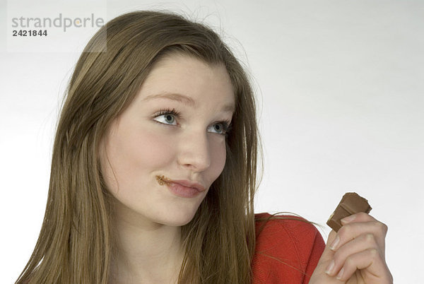 Brünettes Mädchen (13-14) beim Schokoladenessen  Portrait