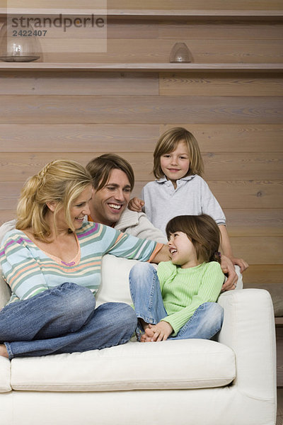 Familie auf Sofa sitzend  lächelnd  Portrait