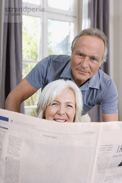 Ältere Frau mit Zeitung  älterer Mann dahinter  Porträt