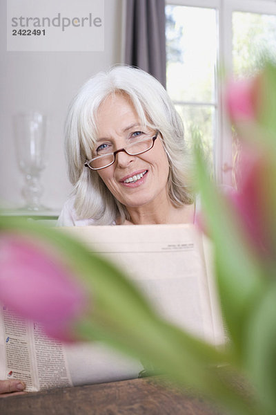 Seniorin mit Zeitung  lächelnd  Portrait