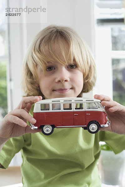 Junge (8-9) hält Spielzeugauto  Portrait