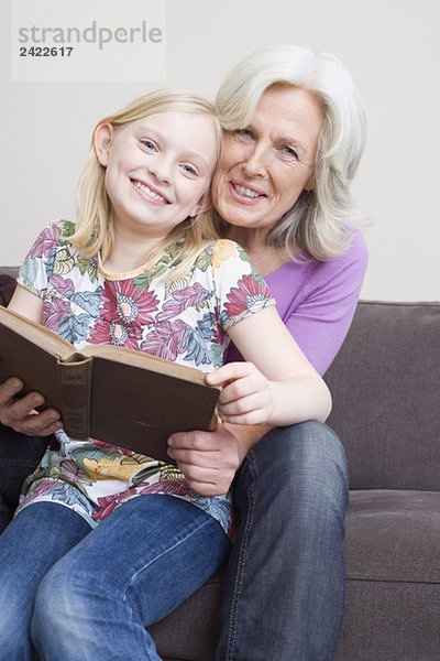 Großmutter und Großmutter (8-9) Lesebuch auf Sofa  Portrait