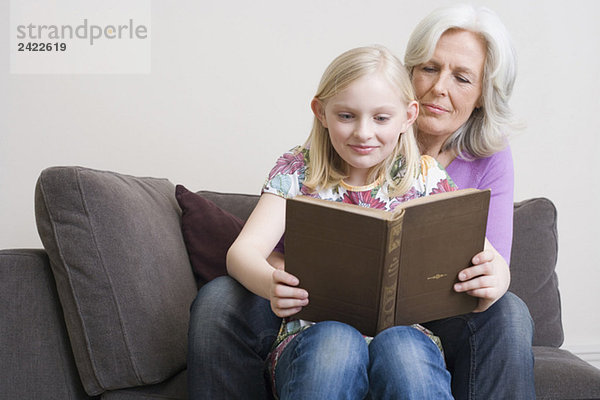 Großmutter und Enkelin (8-9) Lesebuch auf Sofa  Portrait