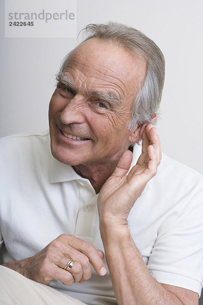 Senior Mann mit Hand an Ohr  lächelnd  Portrait