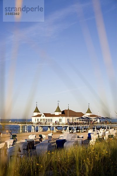 Zusammengerollte Gras und Kapuzen Liegestühle am Strand mit Pier im Hintergrund  Ahlbeck  Usedom  Mecklenburg-Vorpommern Deutschland