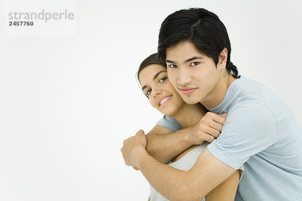 Junges Paar umarmt  lächelnd vor der Kamera