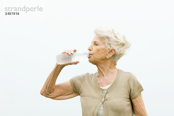 Seniorenfrau trinkt Flasche kaltes Wasser