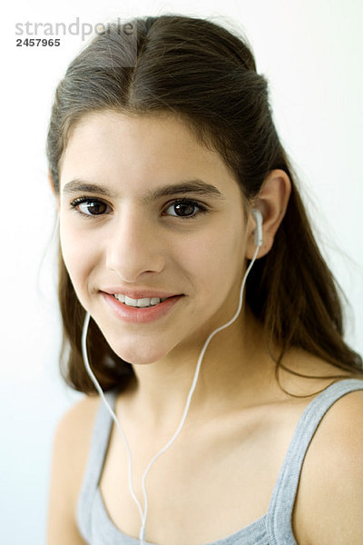 Teenagerin hört Kopfhörer und lächelt in die Kamera