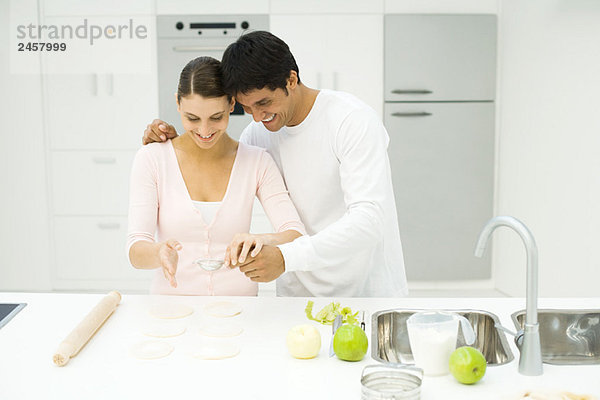 Paar in der Küche  Mehl auf den Teig sieben  lächelnd