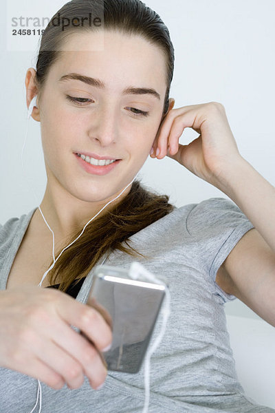 Teenagerin hört MP3-Player  lächelt  schaut runter