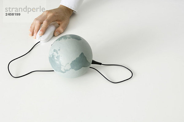 Hand mit Computermaus  die mit dem Globus verbunden ist