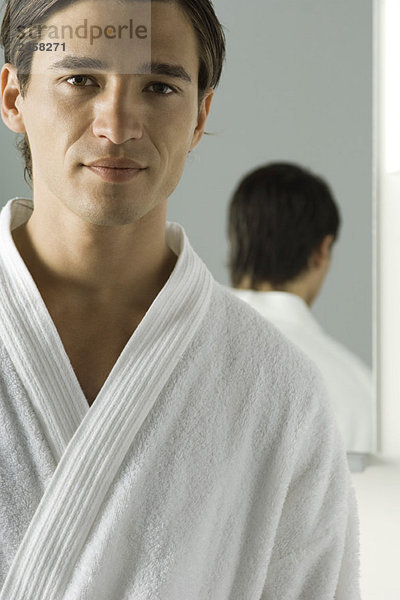 Mann im Bademantel  lächelnd vor der Kamera  Spiegel im Hintergrund
