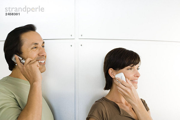 Mann und Frau benutzen Mobiltelefone  schauen weg  lächeln
