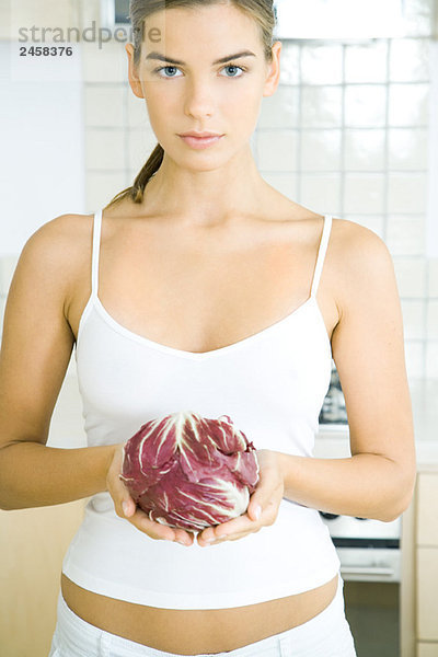 Junge Frau mit einem Kopf aus Radicchio-Salat in der Küche
