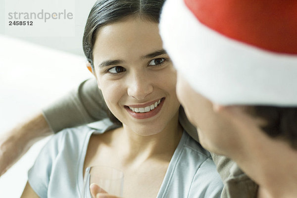 Junge Frau lächelt den Mann mit Weihnachtsmütze an  Nahaufnahme