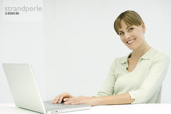 Frau mit Laptop-Computer  lächelnd vor der Kamera
