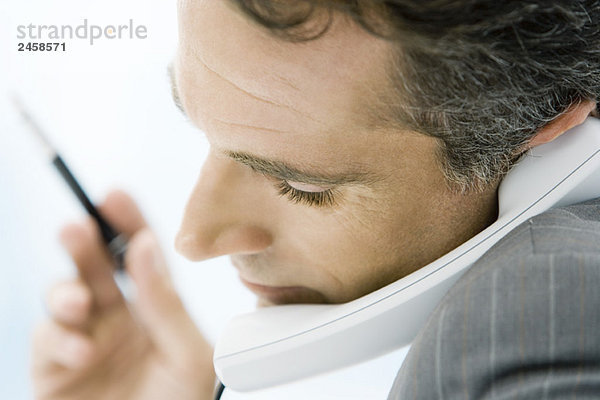 Mann hält Telefon zwischen Kinn und Schulter  Seitenansicht  Nahaufnahme