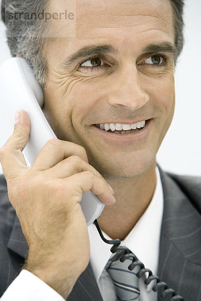 Mann mit Festnetztelefon  lächelnd  wegschauend