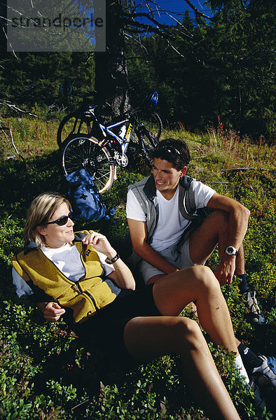 Ein paar ruhen im Gras während einer Radtour tour Schweden.
