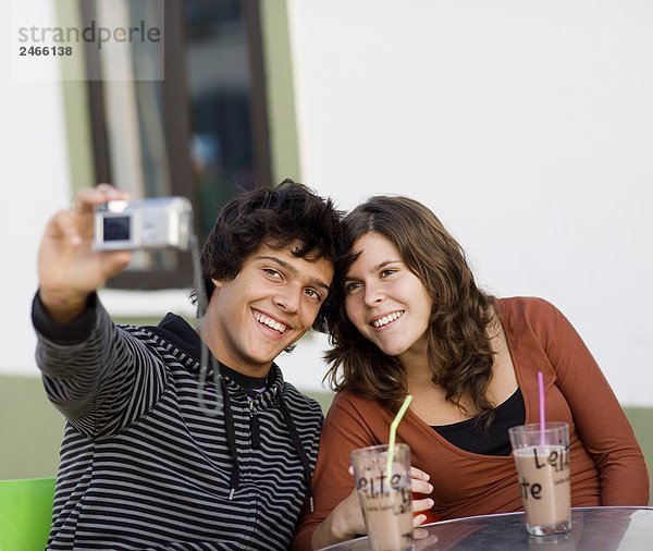 Ein junges paar sitzen an einem Caf Besitz einer Kamera Portugal.