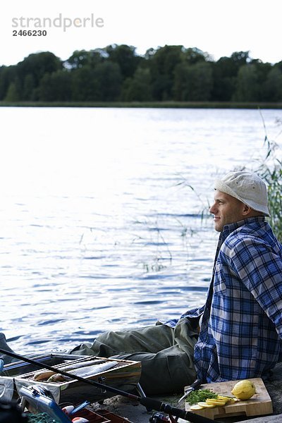 Ein Mann Grillen Fisch am Wasser Schweden.