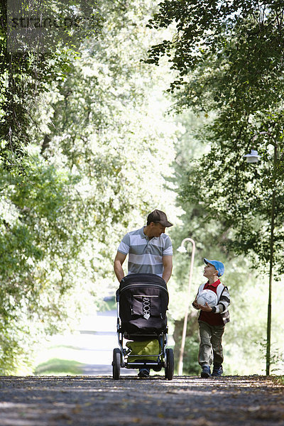 Vater und Sohn zu Fuß in einem Park am sonnigen Tag Schweden.