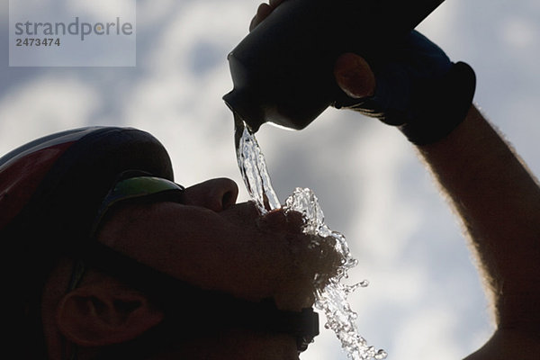 Silhouetted ein Radfahrer Trinkwasser  Seitenansicht