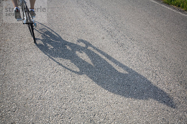 Schatten des ein Radfahrer wirft auf Straße