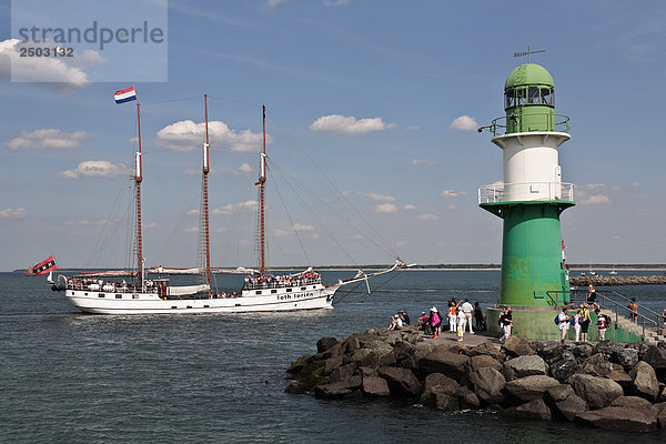 Touristen stehen in der Nähe von Leuchtturm an der K??ste  Warnemunde  Mecklenburg-Vorpommern  Berlin  Deutschland