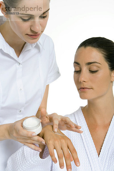 Kosmetikerin beim Auftragen der Feuchtigkeitscreme auf die Hand der Frau