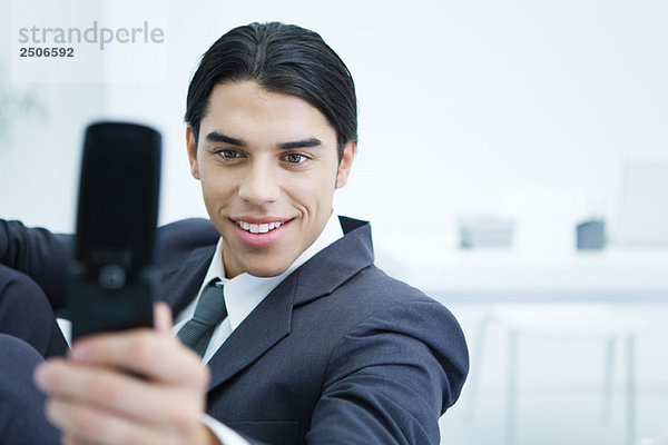 Junger Geschäftsmann mit dem Handy  um sich selbst zu fotografieren  lächelnd