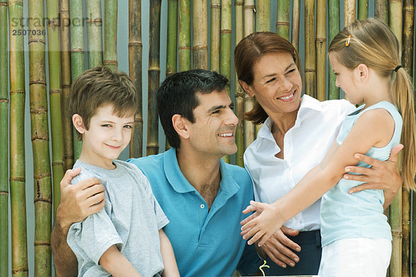 Familie lächelt sich vor Bambus an  Gruppenporträt  Junge schaut in die Kamera