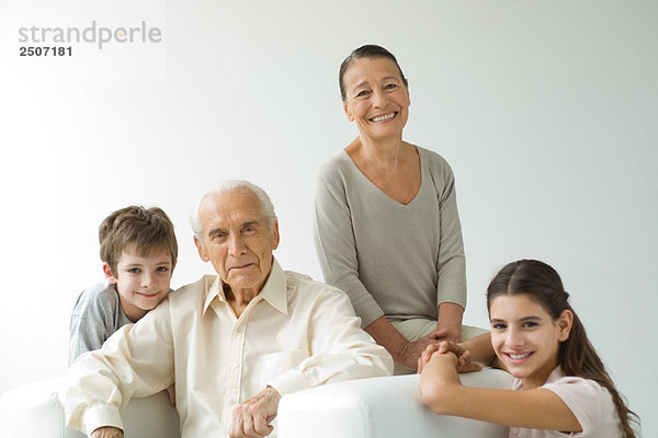 Großeltern sitzend mit Enkelkindern  alle lächelnd  Portrait